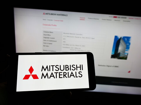 Stuttgart, Germany - 09-11-2022: Person holding smartphone with logo of company Mitsubishi Materials Corporation (MMC) on screen in front of website. Focus on phone display.