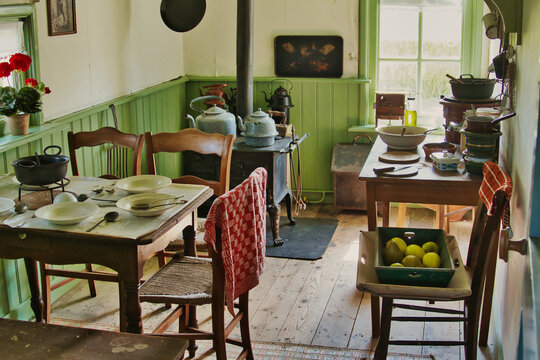 Leens, Netherlands, 4-24-2022. Traditional kitchen in a 19th-century Dutch farmworker's cottage, with a set table, wood stove, kettles and a sloped wooden ceiling. Verhildersum, province of Groningen.