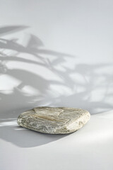 Natural marble and concrete pedestal with dark shadows of leaves. Empty showcase for packaging...