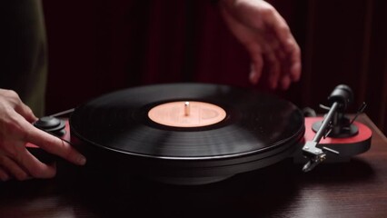 man puts a record on a vinyl player. dark room. close-up.