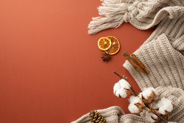 Winter concept. Top view photo of knitted scarf dried orange slices pine cone anise cinnamon sticks and cotton branch on isolated brown background with copyspace