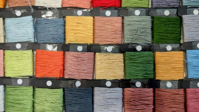 slow movement along an even row of bobbins with floss threads. goods for hobbies, creativity and embroidery, cross-stitching and quilting. Different collors 