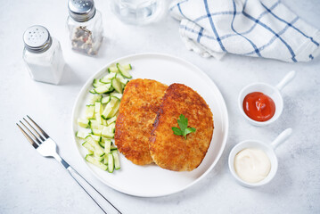 Fresh prepared schnitzel in a plate with fresh cucumber slices