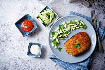 Fresh prepared schnitzel in a plate with fresh cucumber slices