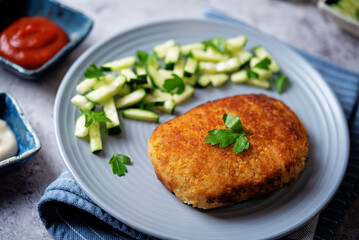 Fresh prepared schnitzel in a plate with fresh cucumber slices