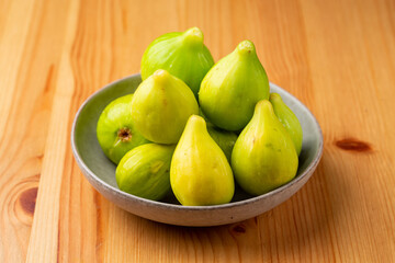 A few green Figs in a bowl isolated on wooden table
