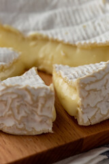 Fototapeta na wymiar Camembert Cheese pieces close-up on a wooden cut board