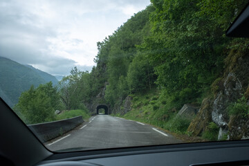 Kyrping, Norway - June 9, 2022: the old Akra Fjord road, POV from a Tesla Model 3 driving on the scenic route. Tunnel and bridges in a cloudy spring day. Selective focus - obrazy, fototapety, plakaty