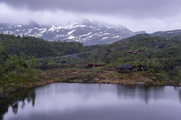 Naklejka na ściany i meble Wonderful landscapes in Norway. Vestland. Beautiful scenery of houses with grass roof. Norwegian traditional architecture Mountains, trees and snow in background. Cloudy day. Selective focus