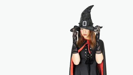 Beautiful girl in witch costume and witch hat is over isolated white background