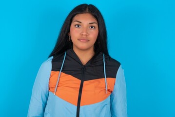 Joyful young beautiful woman wearing sport outfit against blue wall looking to the camera, thinking...