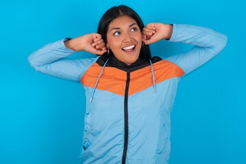 young beautiful latin woman wearing sportswear  relaxing and stretching, arms and hands behind head and neck smiling happy