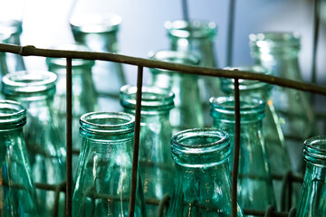 Metal crate of glass antique milk bottles on steps of house. Delivery of dairy products, milkman