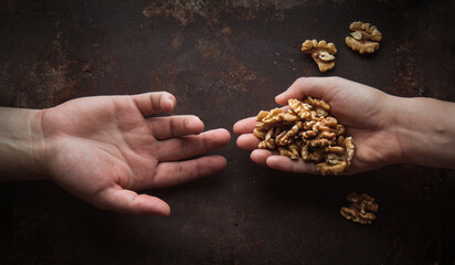 Foto conceptual de manos de personas compartiendo nueces sobre mesa rústica