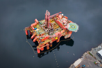 Aerial view of an offshore oil drilling platform and maintenance dock in a fjord in Norway