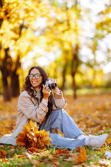 Portrait of  beautiful woman taking pictures in the autumn forest. Smiling woman enjoying autumn weather. Rest, relaxation, lifestyle concept.