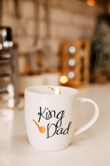 On the kitchen decorated with Christmas garlands there is a white cup of dad