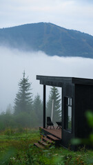 Black wooden cabin above clouds on Carpathian mountains in Ukraine