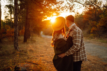Young couple having fun walking and hugging on autumn park at sunset. People, lifestyle, relaxation and vacations concept.