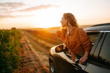 Young woman is resting and enjoying sunset in the car. Lifestyle, travel, tourism, nature, active life.