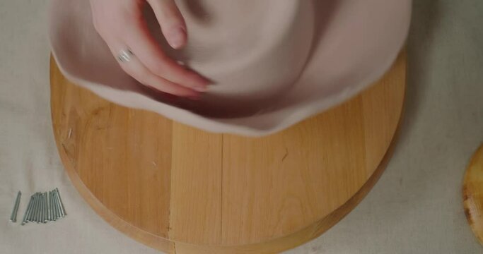 Hands of woman stretch material of felt hat to make brim