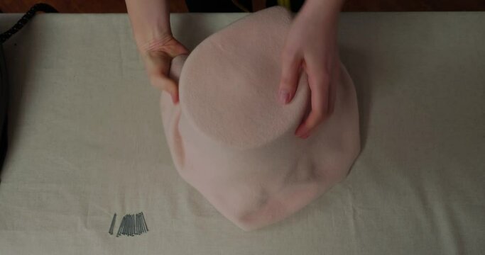 Professional hat-maker pulls felt body on mold to make shape