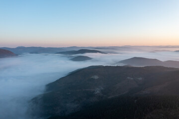 aerial view of morning lights, sun shines over clouds and plateau houses and trees with blue sky and foggy mountains