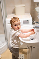 Fototapeta na wymiar Smiling cute little girl child washing hands in bathroom
