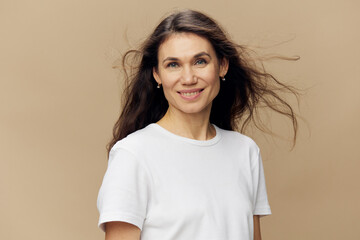 portrait of a sweet, beautiful, charming, pleasant woman with black hair, blowing in the wind, in a white T-shirt. Studio photo on a plain background