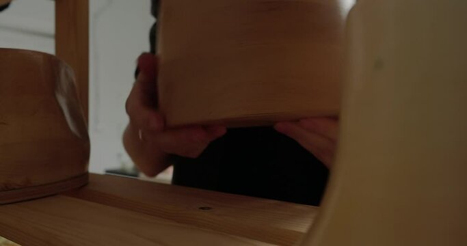 Professional milliner takes wooden mold standing on shelf