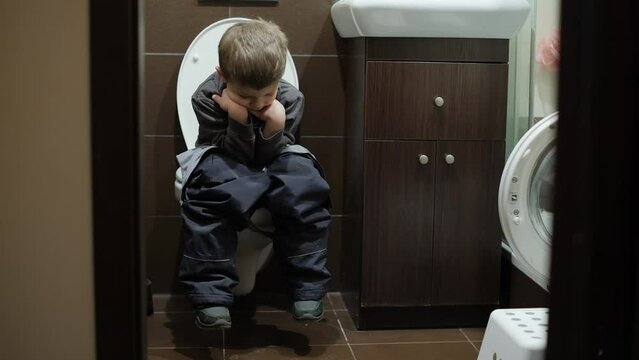 a boy sits on the toilet in the restroom