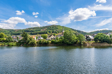 Obraz premium Some houses at the shore of lake Rursee, In the middle of the Eifel National Park, surrounded by unique natural scenery and unspoilt nature