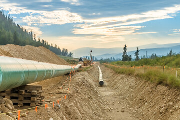 Pipeline construction work in progress in mountain area with haze from summer fires and morning mist
