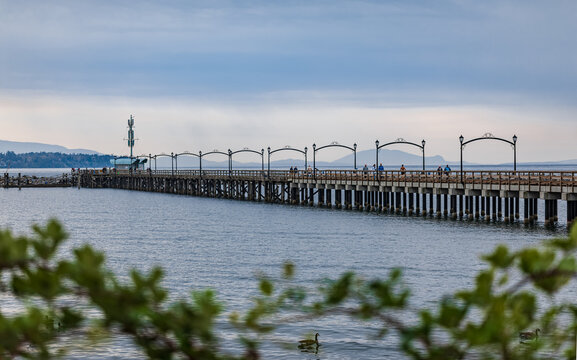 Wooden pier at White Rock, BC, Canada extends diagonally into image. City of White Rock Pier at overcast cloudy day