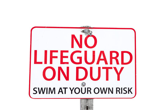 A red and white sign on a wooden post indicating No Lifeguard on Duty swim at your own risk at the beach