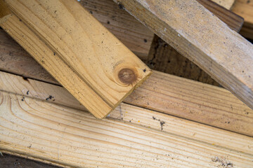 Stacked sawn wooden boards lie on the ground, texture of wooden planks