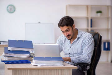 Young male employee and too much work in the office