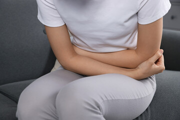 Fototapeta na wymiar Woman suffering from cystitis on sofa at home, closeup