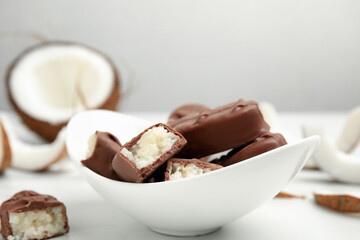 Delicious milk chocolate candy bars with coconut filling on white table, closeup. Space for text