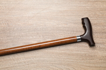 Elegant walking cane on wooden table, top view