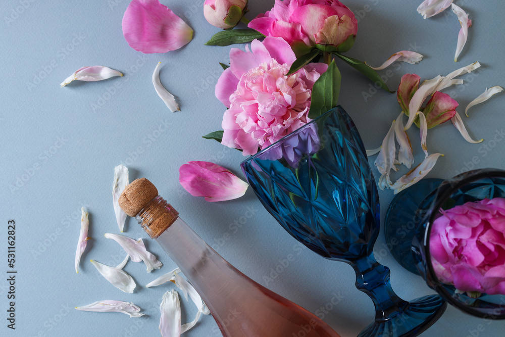 Sticker Flat lay composition with bottle of rose wine, glasses and beautiful pink peonies on grey background