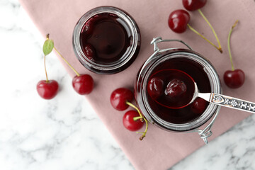 Jars of pickled cherries and fresh fruits on white marble table, top view