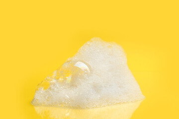 Drop of fluffy bath foam on yellow background
