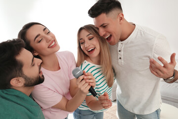 Happy friends singing karaoke together at home