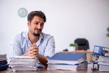 Young male employee and too much work in the office