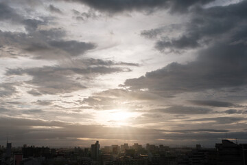 厚い雲に覆われた東の空から太陽が姿を表し。高層ビルがシルエットで浮かび上がる。早朝神戸市内より芦屋大阪方面を臨む。