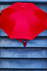 Woman under a red umbrella walking down the stairs to the underground. Business executive woman concept.