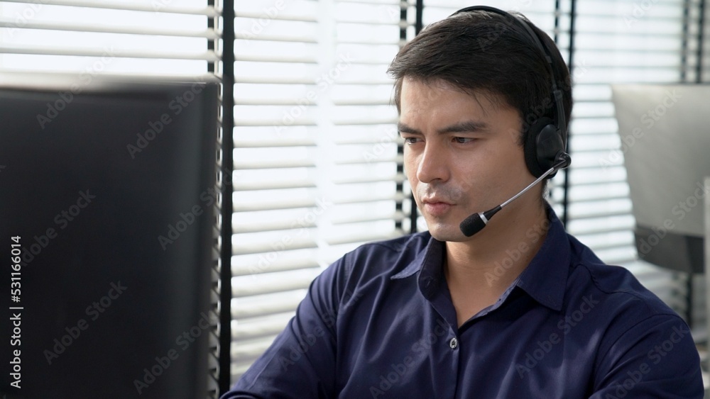 Aufkleber young competent asian male call center agent working at his computer while simultaneously speaking w