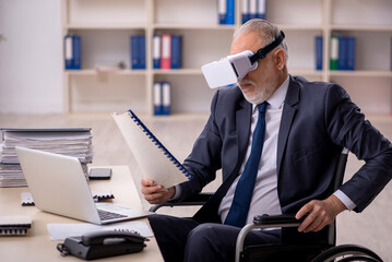 Old leg injured male employee wearing virtual glasses at workpla
