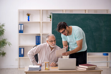 Old male teacher and young male student in the classroom